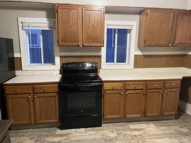 kitchen featuring black appliances, extractor fan, and light wood-type flooring