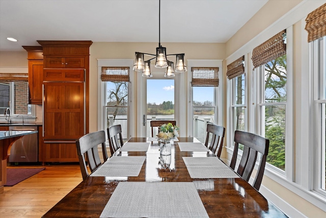 dining room featuring sink, light wood-type flooring, and a notable chandelier
