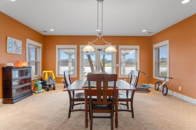 dining space featuring light carpet, an inviting chandelier, and a healthy amount of sunlight