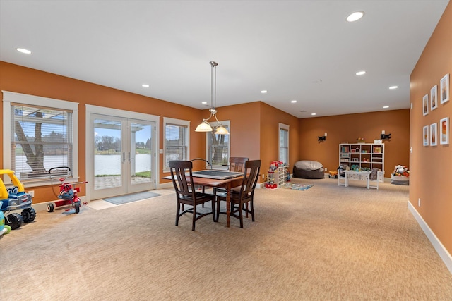 dining room with light carpet, french doors, and a water view