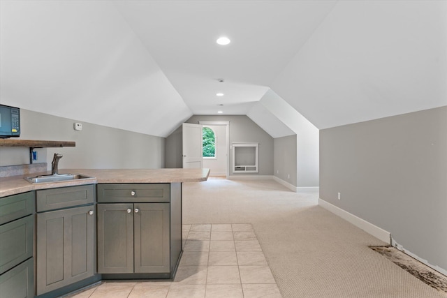 kitchen with light carpet, gray cabinets, lofted ceiling, and sink