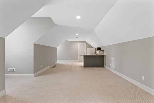 bonus room featuring sink, light colored carpet, and vaulted ceiling