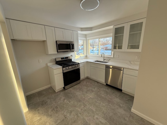 kitchen featuring sink, stainless steel appliances, white cabinetry, and light stone countertops