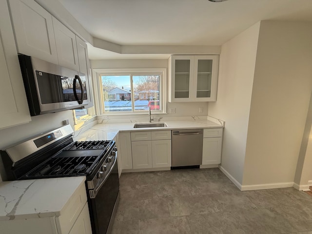 kitchen featuring light stone counters, stainless steel appliances, white cabinets, and sink