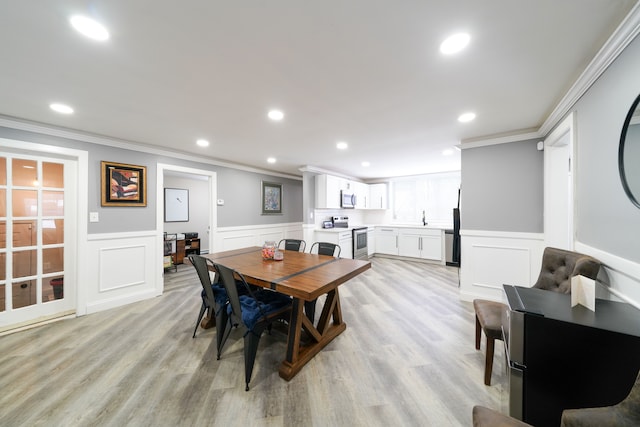 dining area with sink, light wood-type flooring, and crown molding