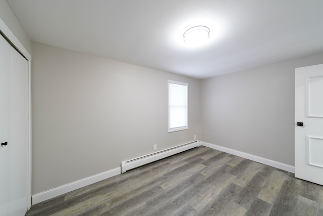 unfurnished bedroom with dark hardwood / wood-style flooring, a baseboard radiator, and a closet