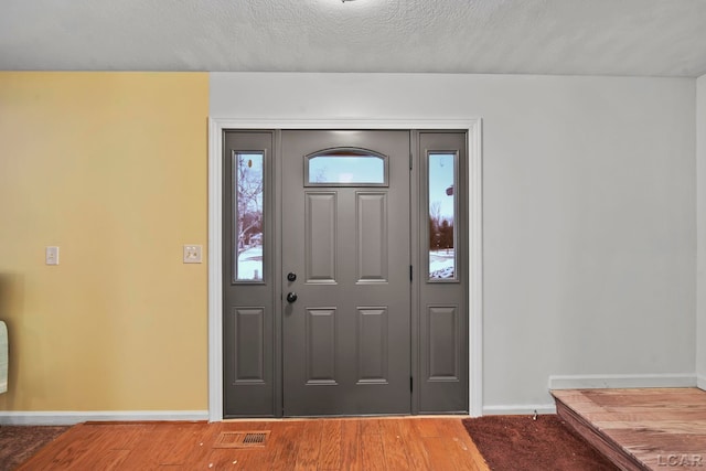 foyer entrance featuring a textured ceiling and hardwood / wood-style flooring