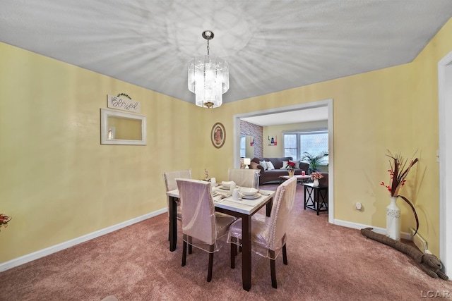 dining space with carpet and a chandelier