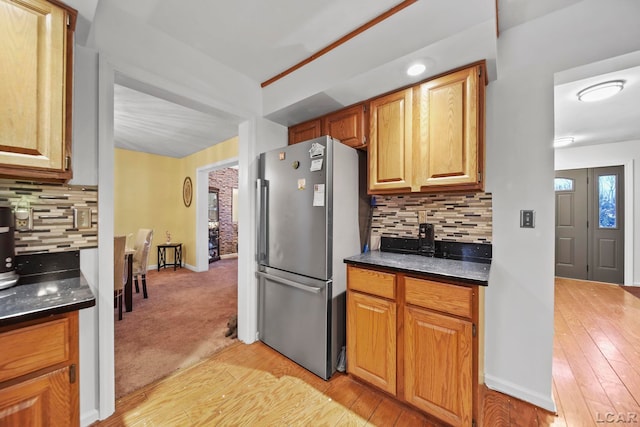 kitchen featuring stainless steel refrigerator, decorative backsplash, and light colored carpet