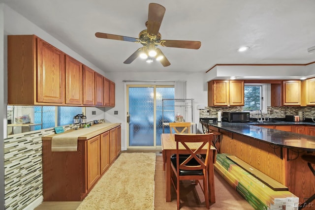 kitchen featuring ceiling fan, tasteful backsplash, a wealth of natural light, and sink