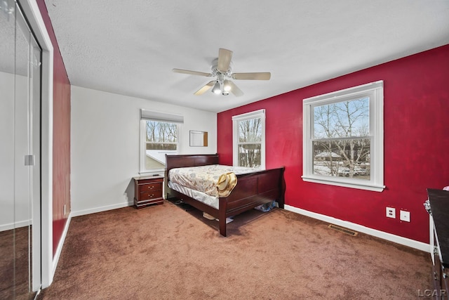 bedroom featuring multiple windows, dark colored carpet, a closet, and ceiling fan