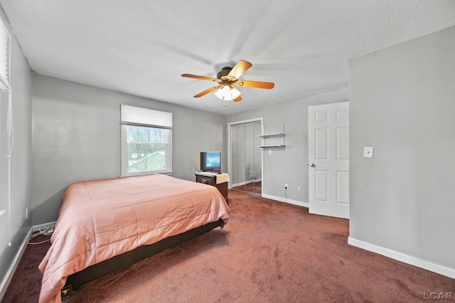 bedroom with ceiling fan, dark carpet, a textured ceiling, and a closet