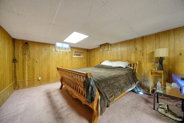 bedroom with a paneled ceiling, wooden walls, and carpet