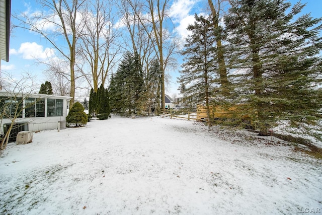 yard covered in snow featuring central AC and a sunroom