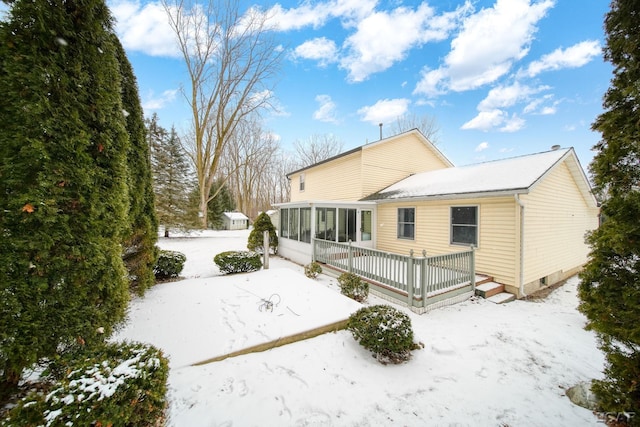 snow covered house featuring a sunroom and a deck