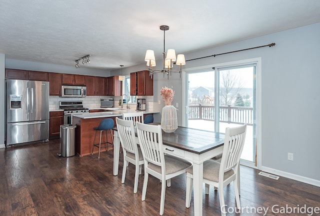 dining room featuring a healthy amount of sunlight, dark hardwood / wood-style flooring, and a notable chandelier