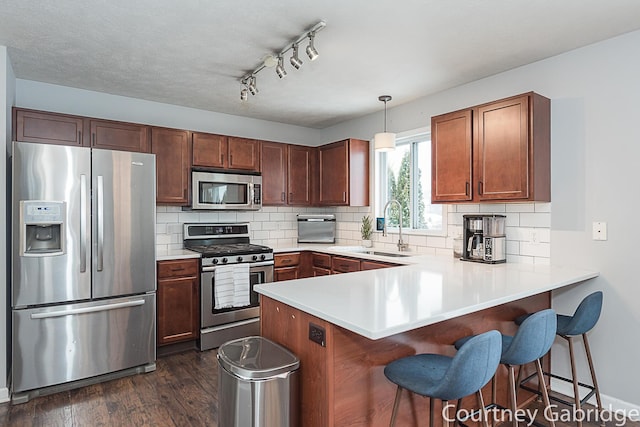 kitchen with pendant lighting, sink, kitchen peninsula, and stainless steel appliances