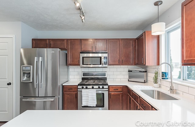 kitchen featuring rail lighting, tasteful backsplash, stainless steel appliances, sink, and pendant lighting