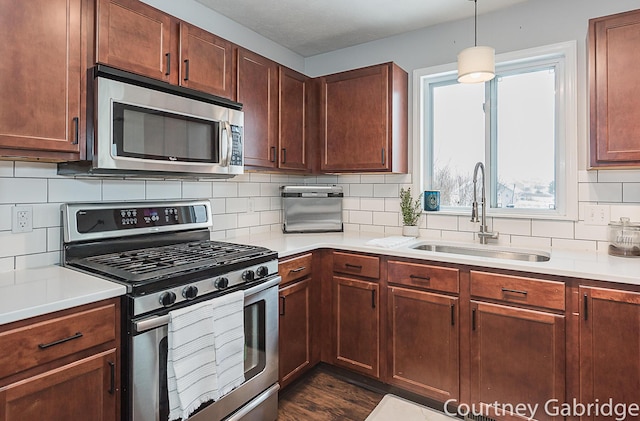 kitchen with tasteful backsplash, sink, pendant lighting, and appliances with stainless steel finishes