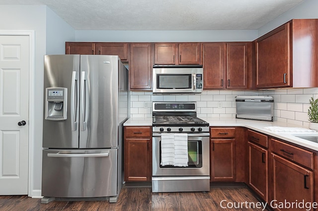 kitchen featuring backsplash, dark hardwood / wood-style flooring, stainless steel appliances, and a textured ceiling