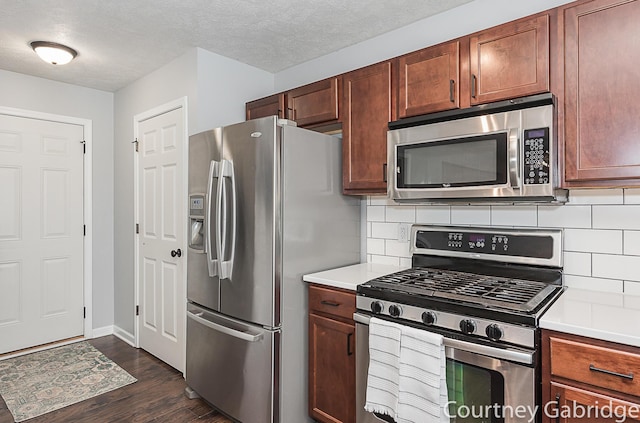 kitchen featuring decorative backsplash, dark hardwood / wood-style flooring, a textured ceiling, and appliances with stainless steel finishes