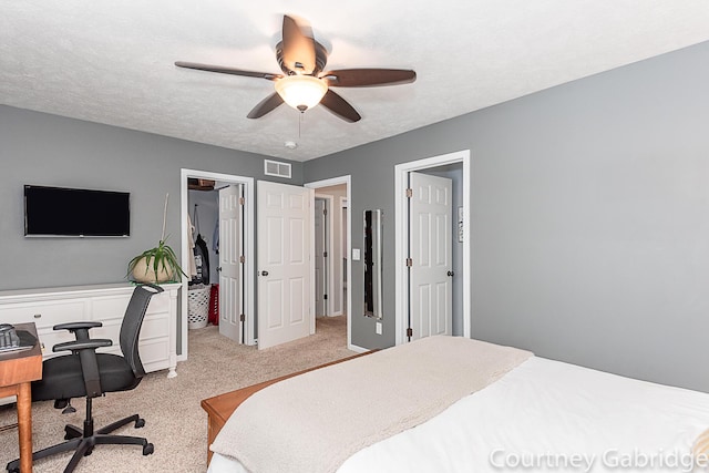 bedroom featuring a textured ceiling, light colored carpet, and ceiling fan