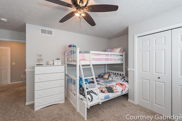 carpeted bedroom featuring a textured ceiling, a closet, and ceiling fan