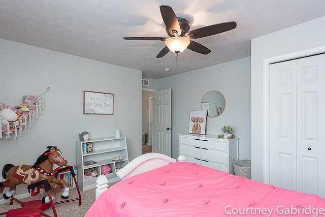 carpeted bedroom with a textured ceiling, a closet, and ceiling fan