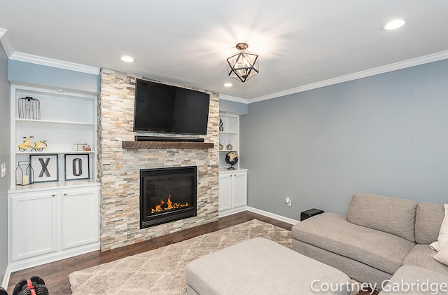 living room featuring built in shelves, dark hardwood / wood-style floors, crown molding, and a fireplace