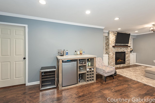 bar with ornamental molding, a fireplace, stainless steel refrigerator, dark hardwood / wood-style flooring, and beverage cooler