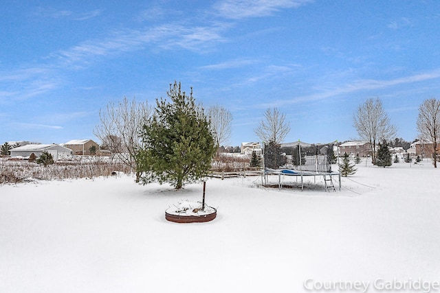 yard layered in snow with a trampoline