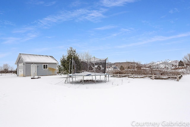 yard covered in snow with an outdoor structure and a trampoline