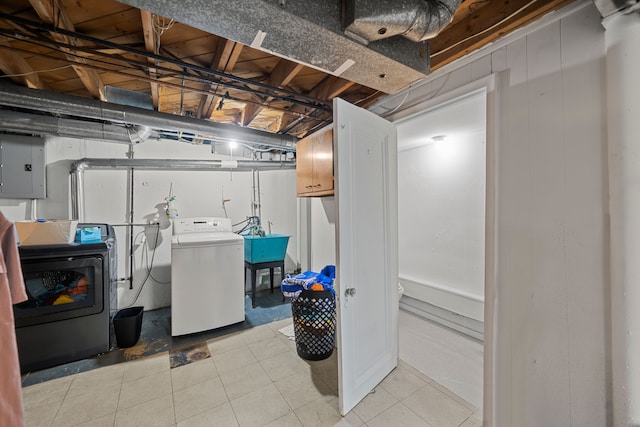 basement featuring light tile patterned floors, electric panel, sink, and washing machine and dryer