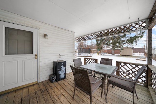 snow covered deck with a trampoline and a shed