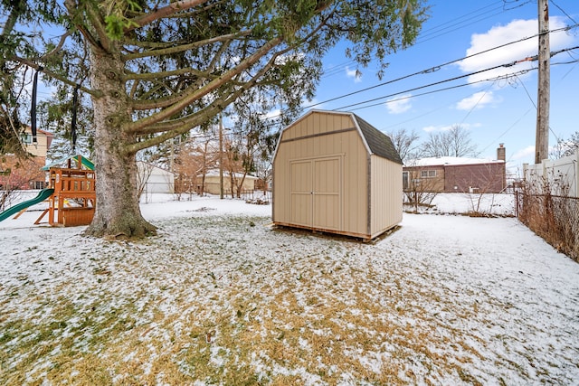 yard layered in snow featuring a shed and a playground