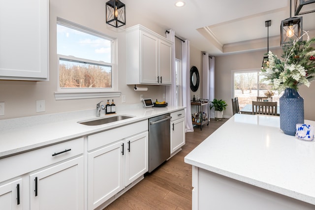 kitchen with light hardwood / wood-style floors, pendant lighting, stainless steel dishwasher, white cabinets, and sink