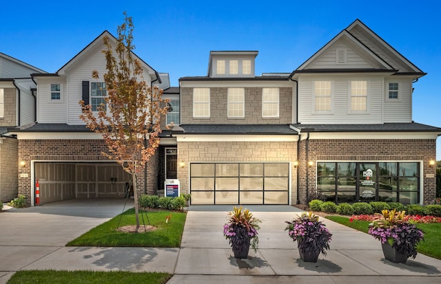 view of front of house featuring a garage, stone siding, brick siding, and driveway