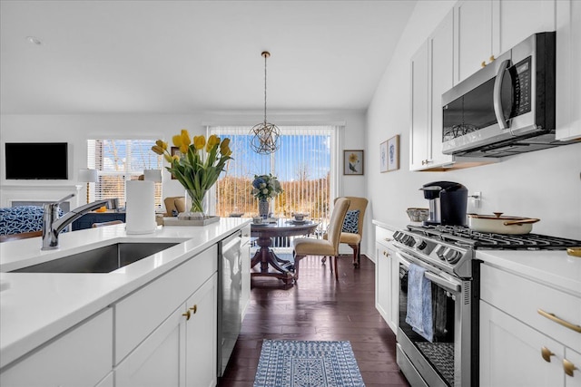 kitchen with appliances with stainless steel finishes, hanging light fixtures, a chandelier, white cabinets, and sink