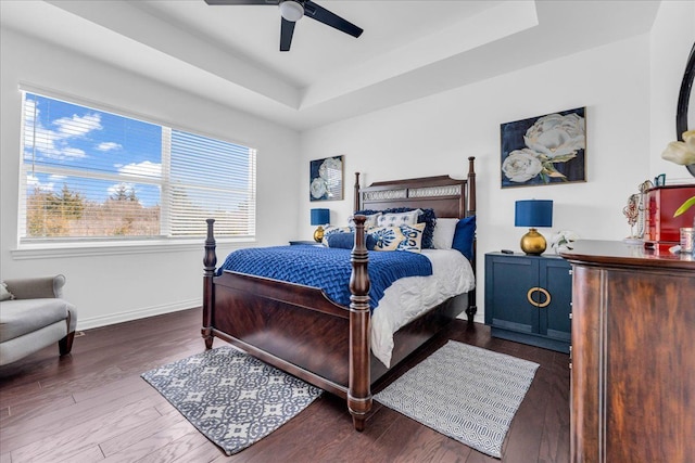 bedroom featuring dark wood-type flooring, ceiling fan, and a tray ceiling