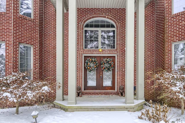 snow covered property entrance featuring french doors