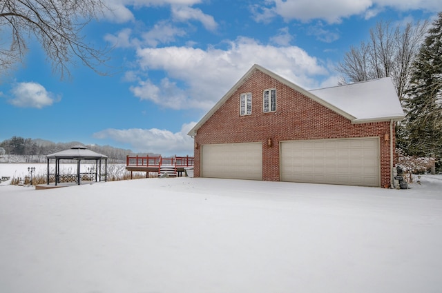 snow covered property featuring a garage and a gazebo