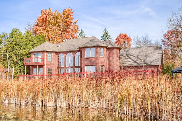 rear view of house with a balcony and a water view