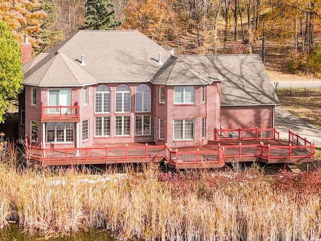 rear view of property featuring a balcony and a deck