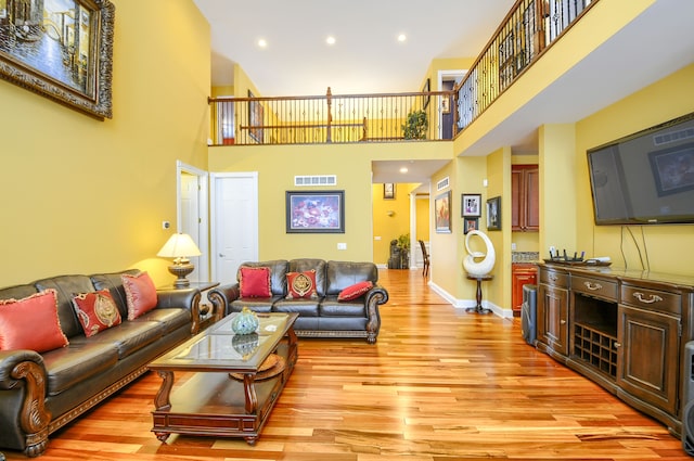 living room featuring a high ceiling and light hardwood / wood-style floors