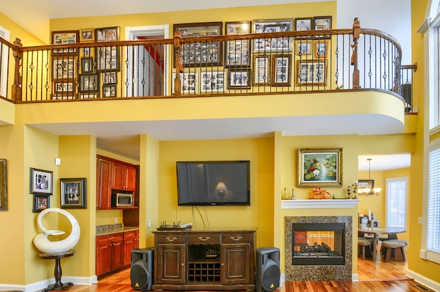 living room featuring light hardwood / wood-style flooring, a multi sided fireplace, and a towering ceiling