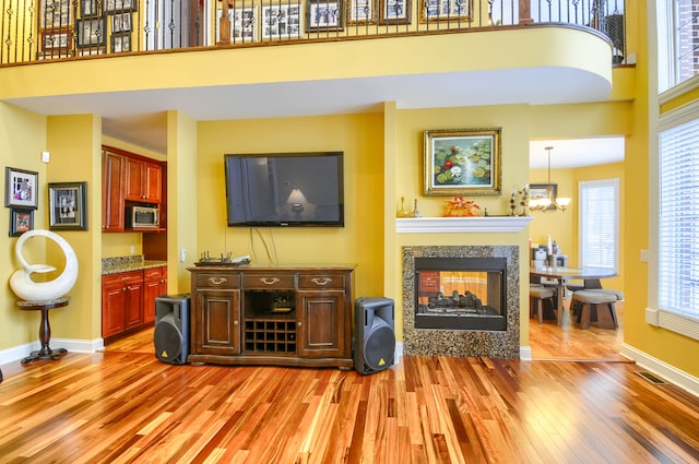 living room with a high ceiling, a multi sided fireplace, and light hardwood / wood-style flooring