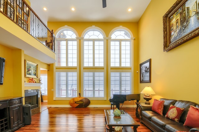 living room featuring a high ceiling, ceiling fan, and wood-type flooring