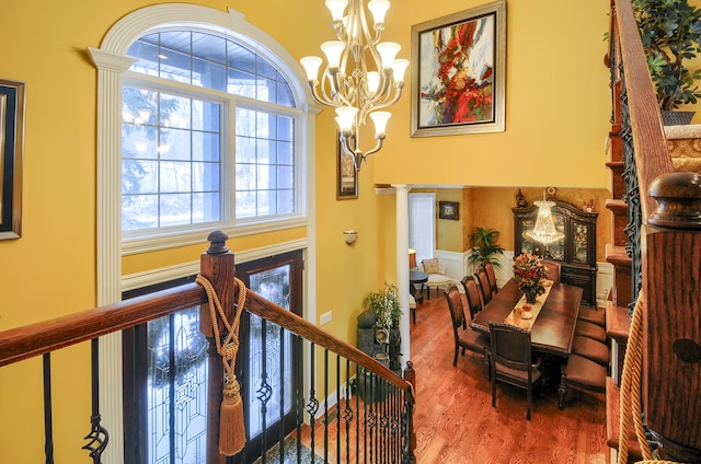 interior space with a healthy amount of sunlight, an inviting chandelier, decorative columns, and hardwood / wood-style flooring