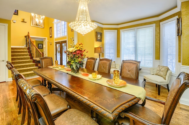 dining space featuring french doors, crown molding, a notable chandelier, and light hardwood / wood-style flooring