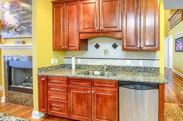 kitchen with sink, hardwood / wood-style floors, dishwasher, and light stone countertops